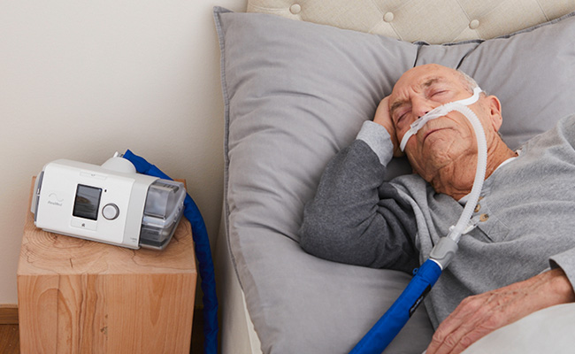 A man sleeping in bed while receiving home high-flow therapy treatment